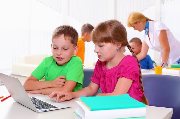 Boy and girl working together on a laptop at school.