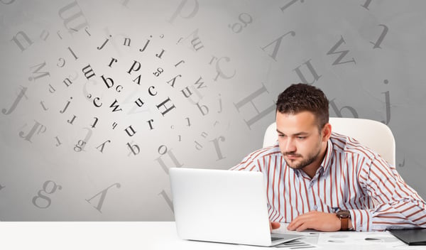 Business person sitting at desk with editorial and letters concept