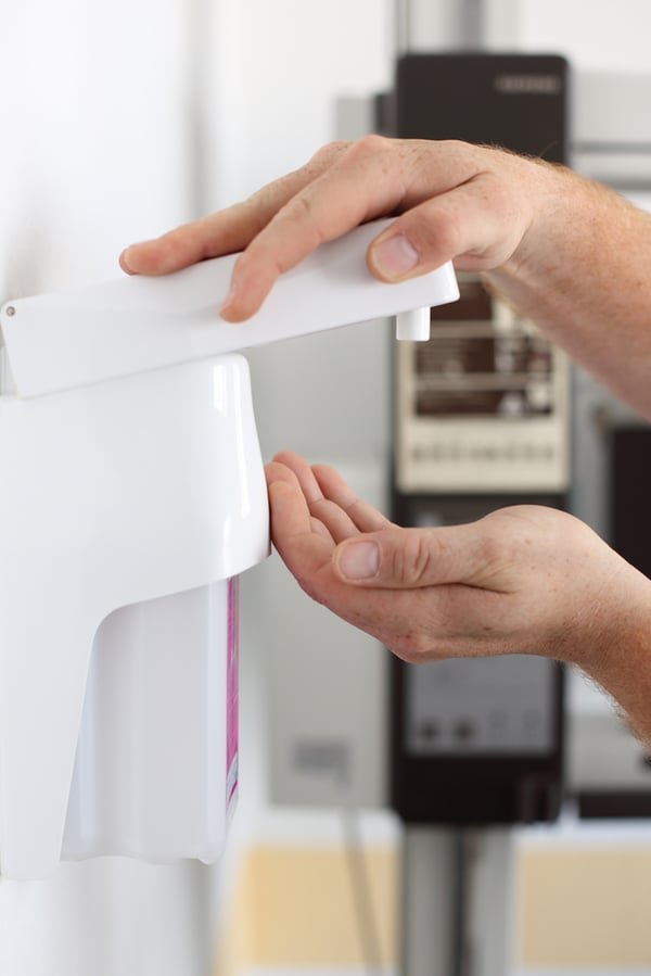 Closeup of dentists hands using soap dispenser in clinic