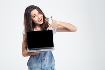 Portrait of a cheerful girl showing blank laptop computer screen isolated on a white background