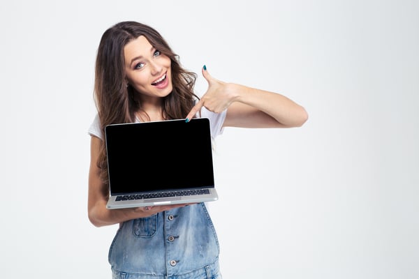 Portrait of a cheerful girl showing blank laptop computer screen isolated on a white background