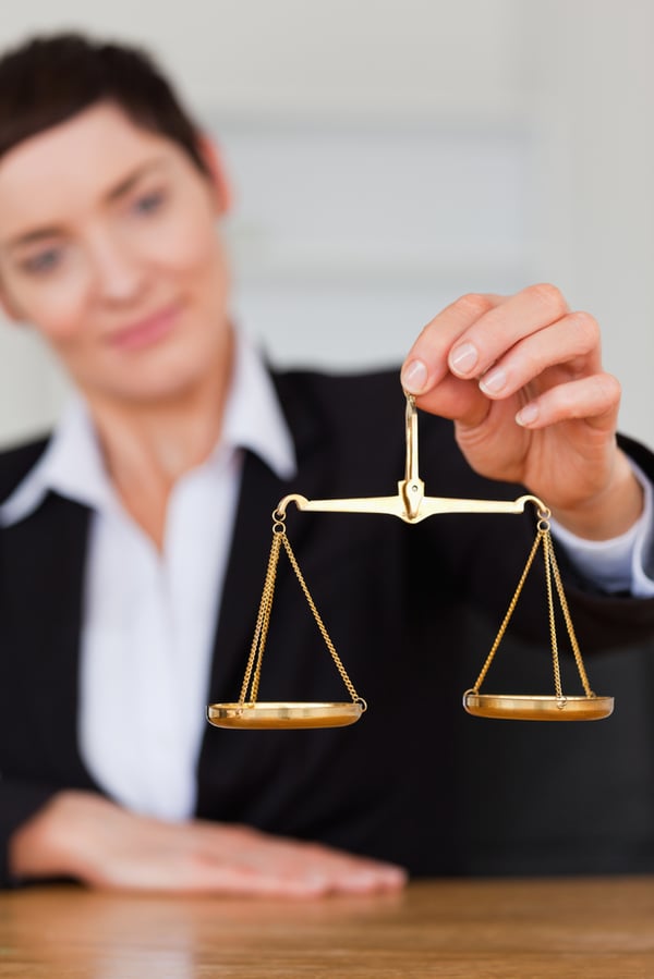 Serious woman holding the justice scale in her office